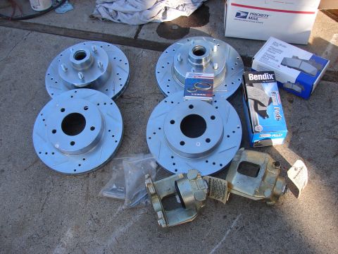 1973 Ford Ranchero - New brake parts laid out on concrete, including rotors, calipers, and brake pads.