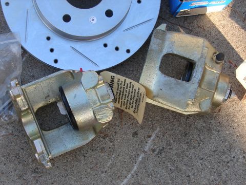 1973 Ford Ranchero - New brake parts, including calipers and a rotor, are laid out on a concrete surface.