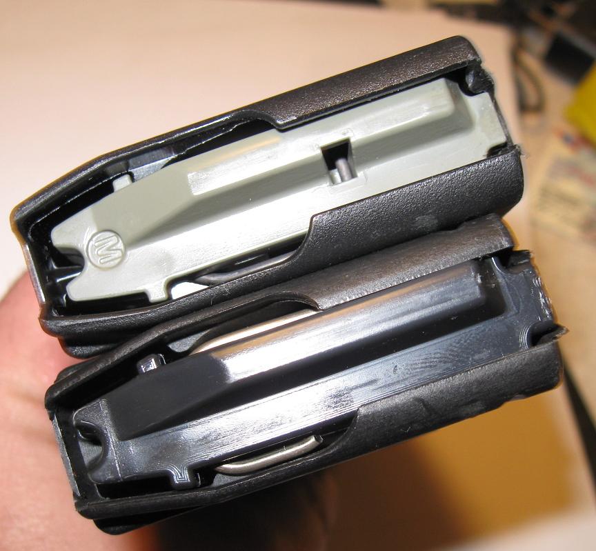 Two firearm magazines held in hand, one with gray follower, one black