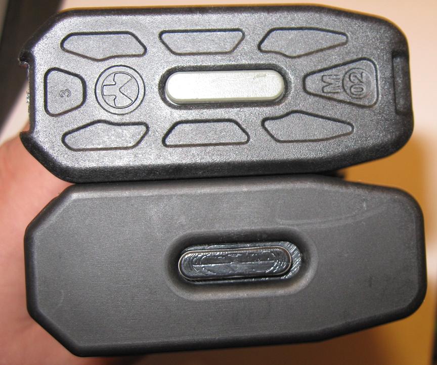 Base plates of two black rifle magazines held in a hand, one with Magpul logo