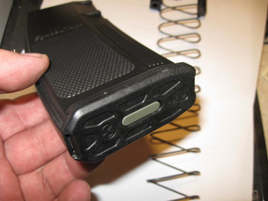 Hand holding a black rugged plastic electronic device over a workbench