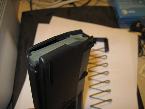 2000 Ford Crown Victoria - A disassembled gun magazine lies on a white surface next to a coiled spring.