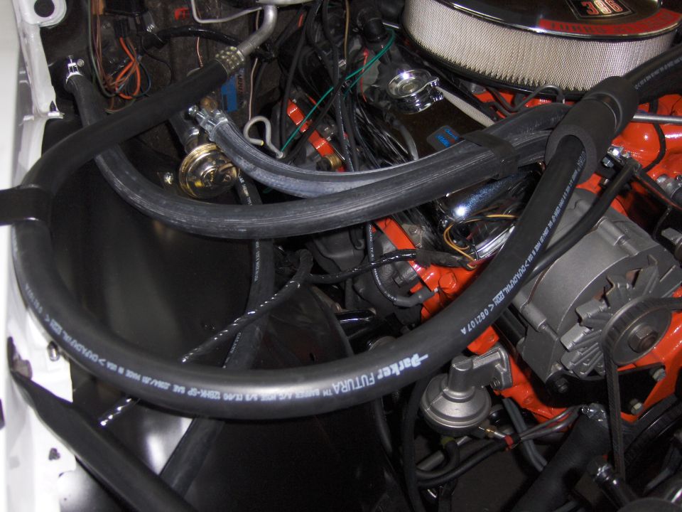 Engine bay with hoses and alternator visible
