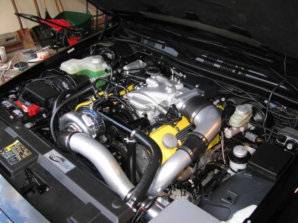 Engine bay with a large turbocharger and custom intake piping. Yellow engine covers visible