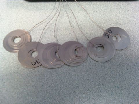 1984 Ford Bronco - Several metal washers, some labeled with measurements, are shown on a textured surface.