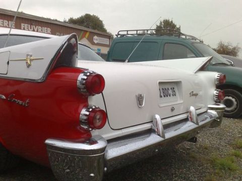 1991 Ford Crown Victoria - A two-tone red and white vintage car is seen from the rear, parked next to other vehicles.