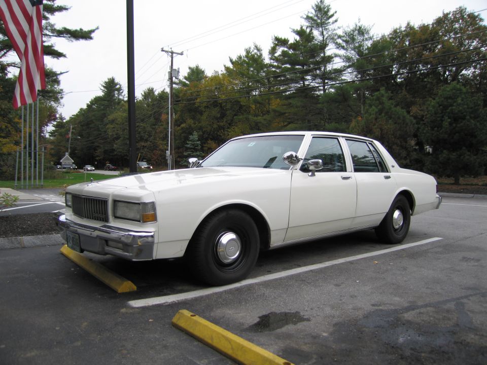 White 1980s Chevrolet Caprice sedan parked in a lot, facing left. It has a chrome grille and bumper