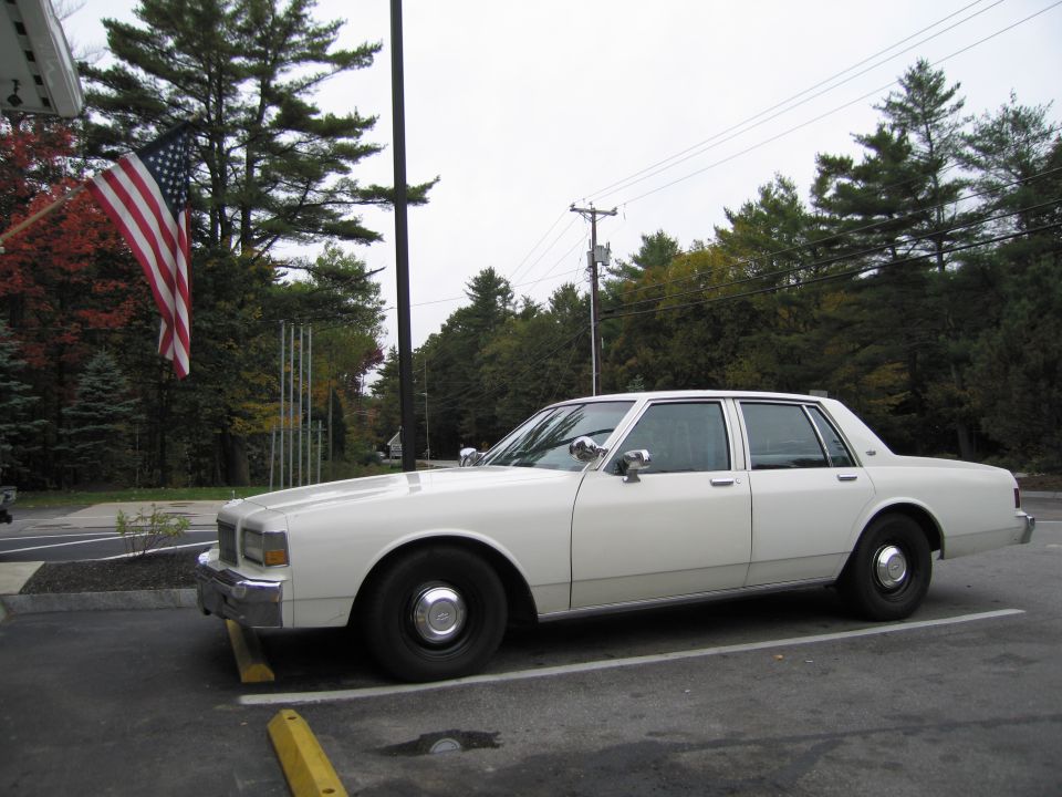 White sedan parked in a lot, side view