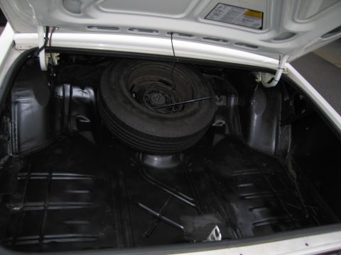 1991 Ford LTD Crown Victoria - The trunk of a white vehicle, showing the spare tire and jack. Some text is visible on the underside of the trunk lid.