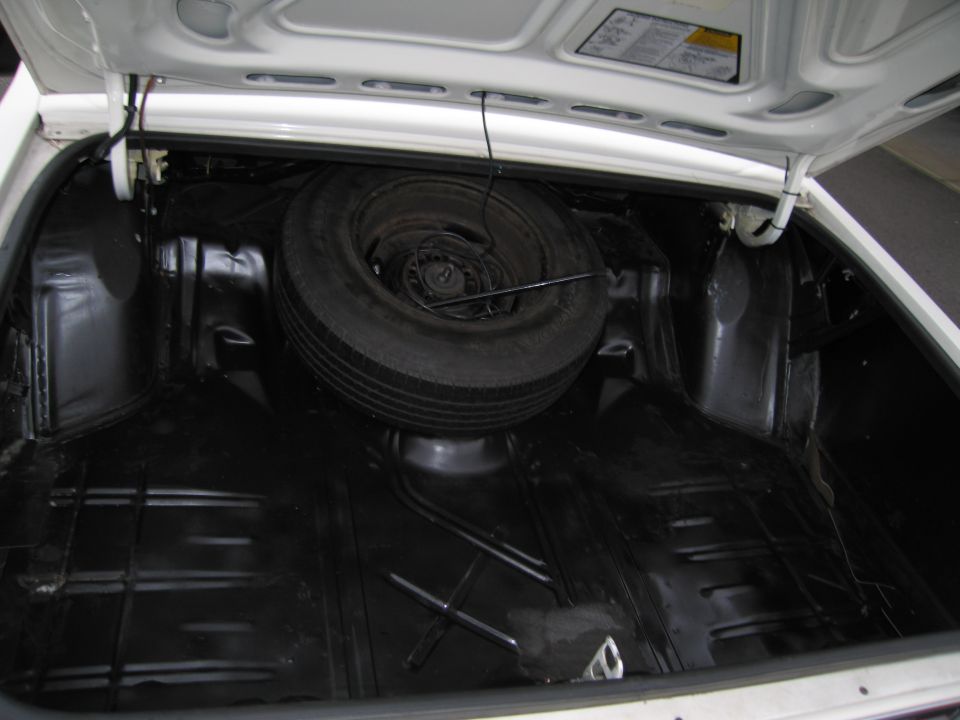 Trunk interior with spare tire and jack. White exterior