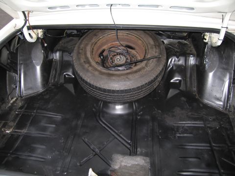1991 Ford LTD Crown Victoria - The trunk of a 1991 Ford Crown Victoria LTD contains a spare tire and jack, with black carpeting on the floor.