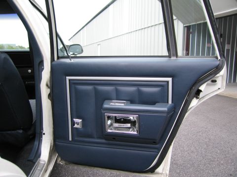 1991 Ford LTD Crown Victoria - Close-up of a blue vinyl door panel with chrome accents, showing the interior door handle and window crank.