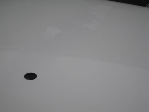 1991 Ford LTD Crown Victoria - A close-up view of a white vehicle panel with a single black circular element.
