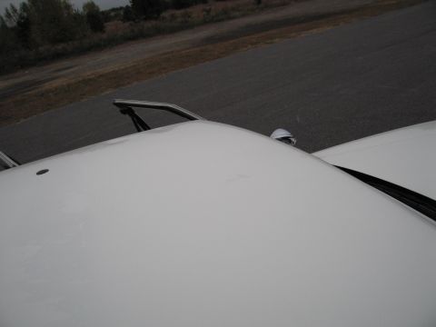 1991 Ford LTD Crown Victoria - A close-up view of a white car's roof and windshield wiper assembly.