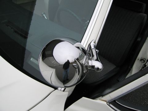 1991 Ford LTD Crown Victoria - A person is reflected in the shiny chrome side mirror of a white vehicle, showing the interior and exterior.