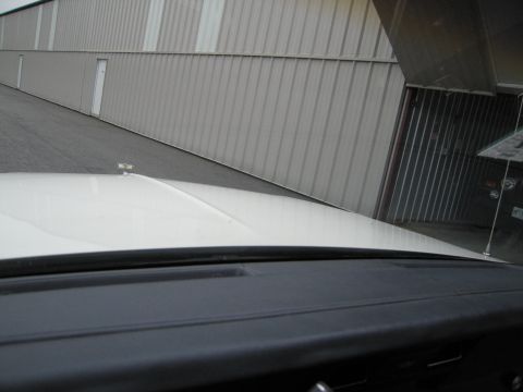 1991 Ford LTD Crown Victoria - View from inside a white vehicle looking towards a grey metal building.