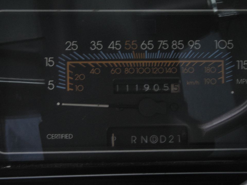 Car dashboard showing a speedometer with mph and km/h scales, an odometer reading 111905.5, and gear selector P R N D 2 1