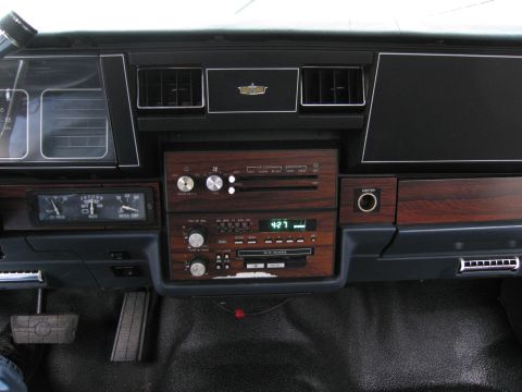 1991 Ford LTD Crown Victoria - The dashboard features a digital clock displaying 4:27 and wood-grain accents around the radio.