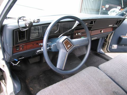 1991 Ford LTD Crown Victoria - Dashboard and steering wheel of a car with wood trim and a Chevrolet emblem.