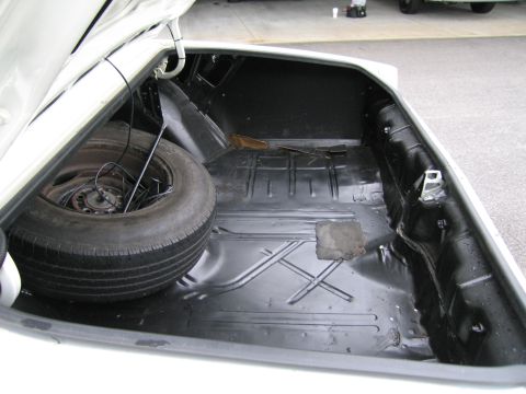 1991 Ford LTD Crown Victoria - The trunk of a car is shown, containing a spare tire and a jack rod.