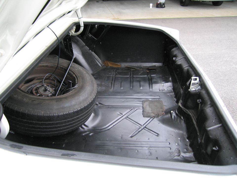 Empty car trunk showing spare tire and jack rod