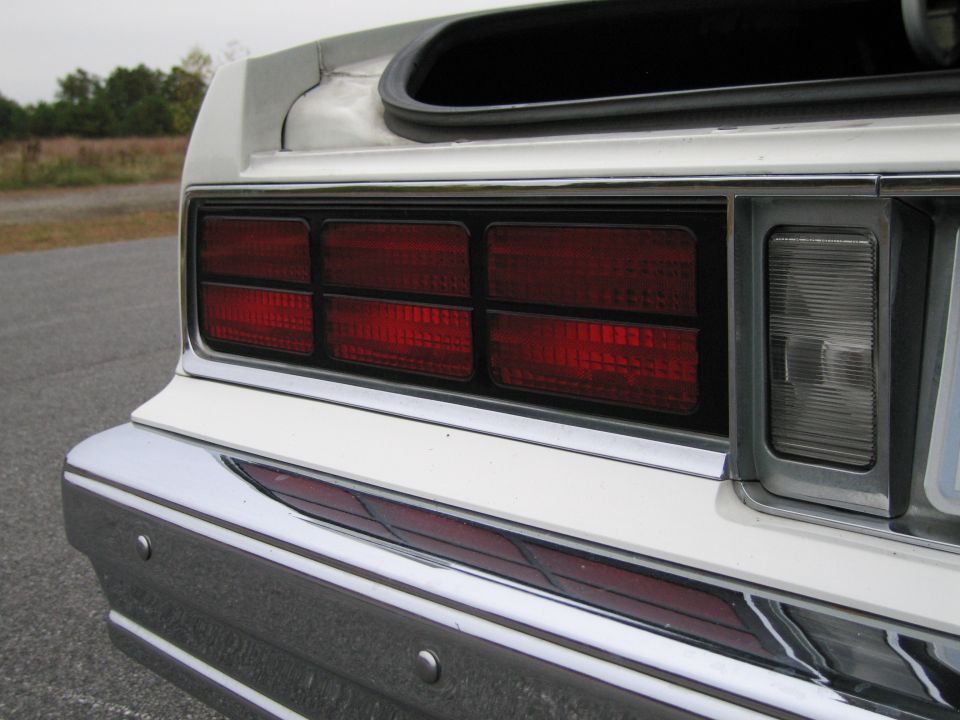 Rear view of a white car showing stacked rectangular taillights and a chrome bumper