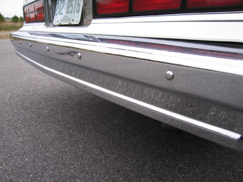 1991 Ford LTD Crown Victoria - Close-up of a car's rear bumper and chrome trim, showing parking sensors.