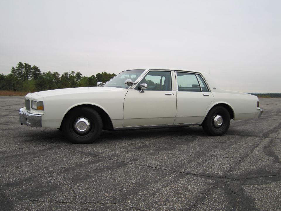 White 1991 Chevrolet Caprice sedan, side view. Police equipment visible