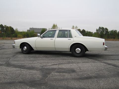 1991 Ford LTD Crown Victoria - This white sedan, likely a 1990 Chevrolet Caprice, is viewed from the side on an overcast day.
