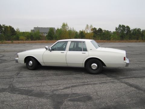 1991 Ford LTD Crown Victoria - Side profile of a white sedan, likely a 1990 Chevrolet Caprice, parked on an asphalt lot.