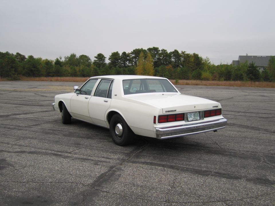 White Chevrolet Caprice sedan parked on asphalt lot, rear view