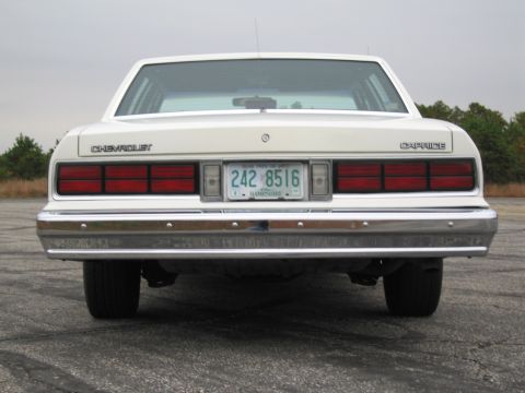 1991 Ford LTD Crown Victoria - Rear view of a white 1980s Chevrolet Caprice sedan, showing its taillights and chrome bumper.