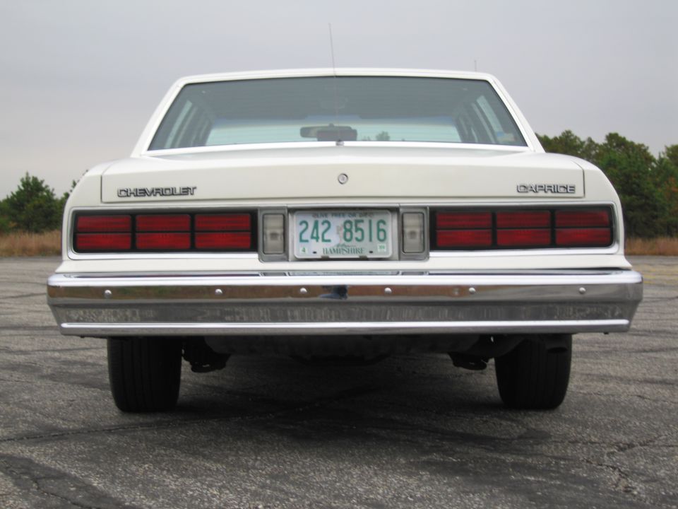 Rear view of a white 1980s Chevrolet Caprice sedan with a New Hampshire license plate reading 242 8516