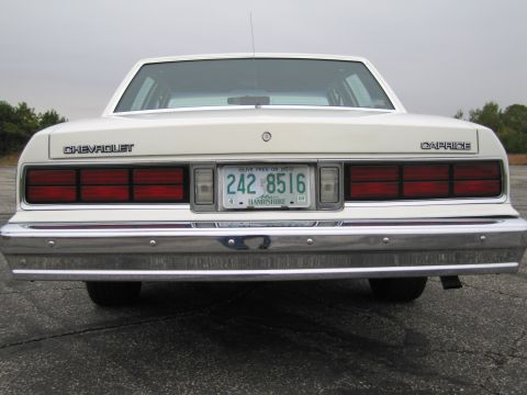 1991 Ford LTD Crown Victoria - The rear of a white Chevrolet Caprice sedan is shown, with its distinctive taillights and chrome bumper.
