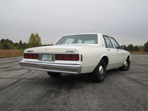 1991 Ford LTD Crown Victoria - Rear view of a white Chevrolet Caprice sedan, likely from the early 1980s, parked on asphalt.