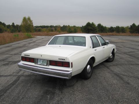 1991 Ford LTD Crown Victoria - Rear view of a white Chevrolet Caprice sedan parked on an empty lot.