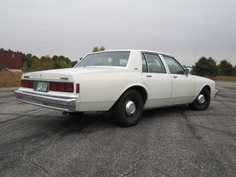 1991 Ford LTD Crown Victoria - This white sedan has a distinctive rear end with rectangular taillights and a chrome bumper.