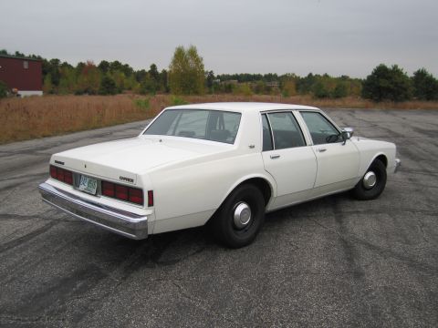 1991 Ford LTD Crown Victoria - This white sedan, identified by its 'Caprice' badging, is a 1980s model, not a 1991 Ford Crown Victoria.