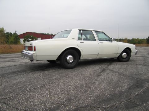 1991 Ford LTD Crown Victoria - This white 1991 Chevrolet Caprice sedan is shown from the rear three-quarter angle.