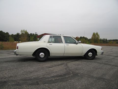 1991 Ford LTD Crown Victoria - Side profile of a white 1991 sedan, likely a Chevrolet Caprice, parked in an open lot.