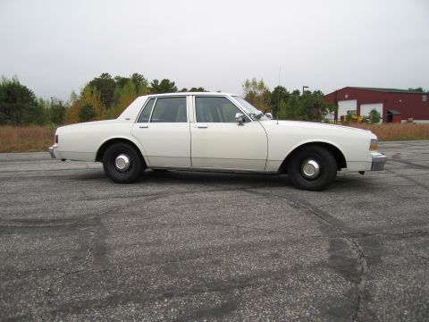 1991 Ford LTD Crown Victoria - Side view of a white sedan with black wheels and chrome trim.