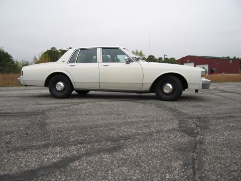 1991 Ford LTD Crown Victoria - This white sedan has a classic boxy body style typical of 1990s American sedans.