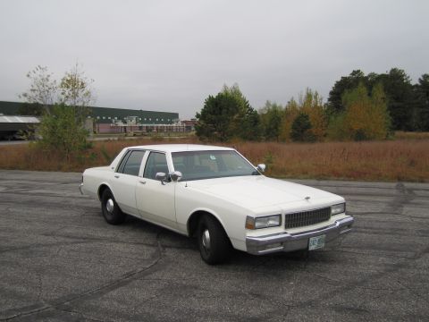 1991 Ford LTD Crown Victoria - White 1980s Chevrolet Caprice sedan parked outdoors on a cloudy day.