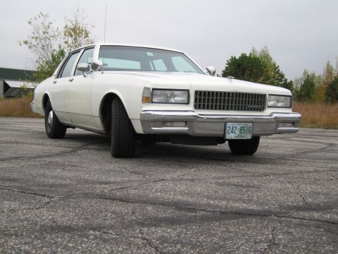 1991 Ford LTD Crown Victoria - This white sedan has a prominent chrome grille and a license plate with readable text.