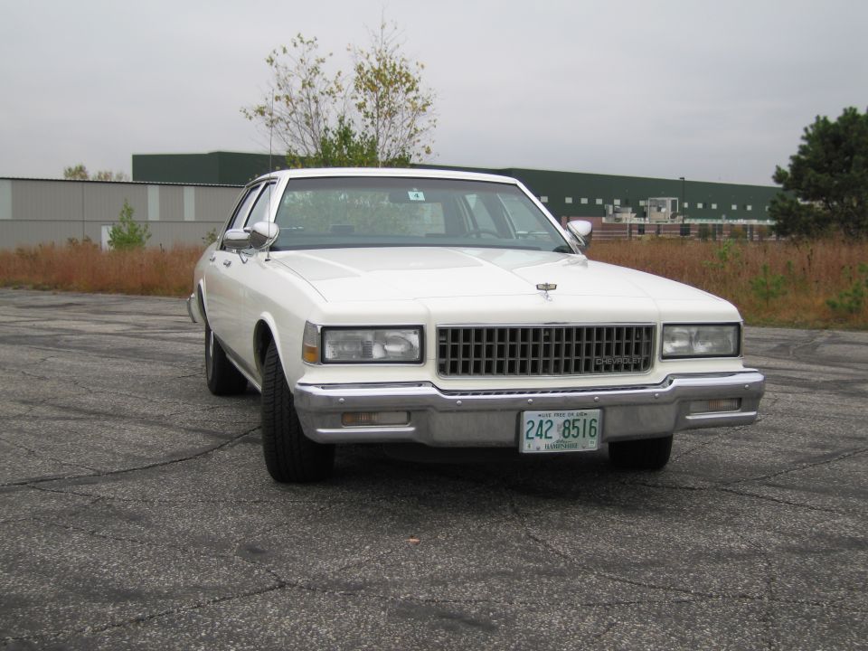 White 1990 Chevrolet Caprice sedan front view with chrome grille and license plate 242 8516