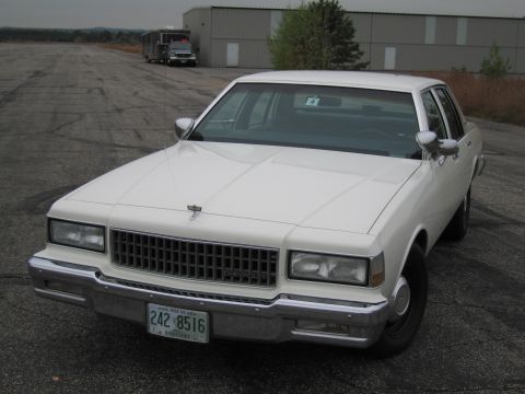 1991 Ford LTD Crown Victoria - This white sedan has a prominent chrome grille and a license plate from Maine.