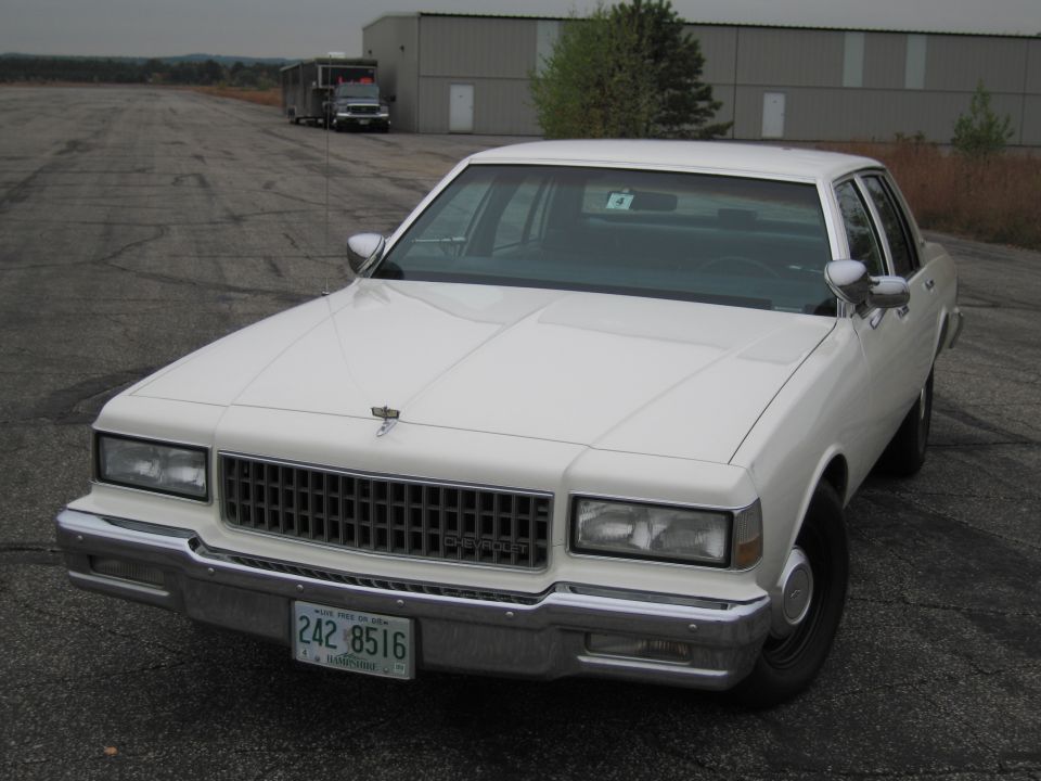 White 1986 Chevrolet Caprice sedan parked on asphalt lot, front quarter view