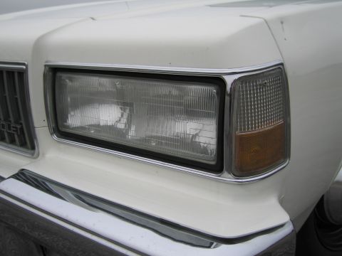 1991 Ford LTD Crown Victoria - Front corner detail of a white vehicle, a rectangular headlight and amber marker light.