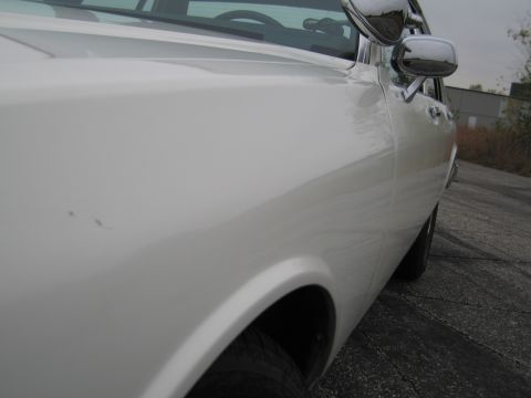 1991 Ford LTD Crown Victoria - Close-up of a white car's side panel and fender, showing a chrome side mirror.