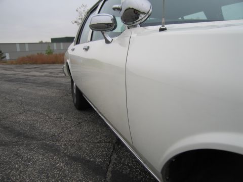1991 Ford LTD Crown Victoria - Side profile of a white vehicle, showing chrome trim along the lower body and a chrome side mirror.